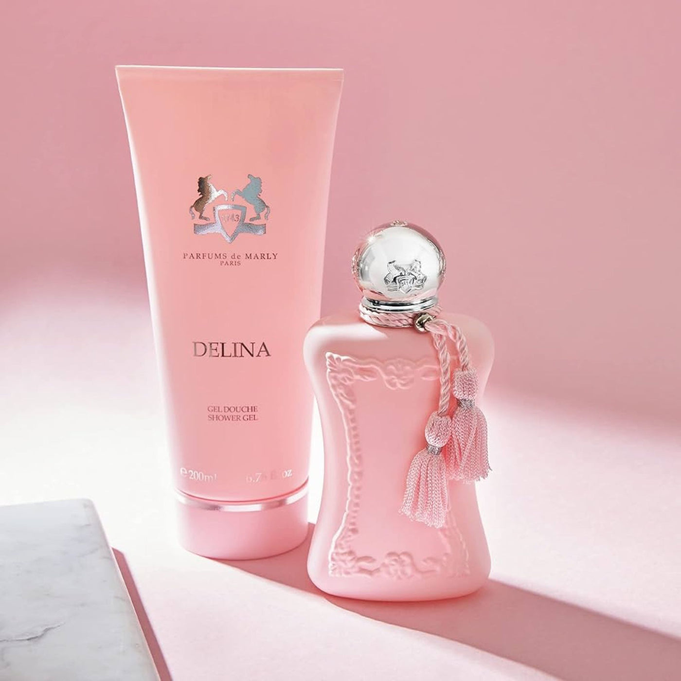 Pink perfume bottle and shower gel with 'Parfums de Marly' branding on a pink background